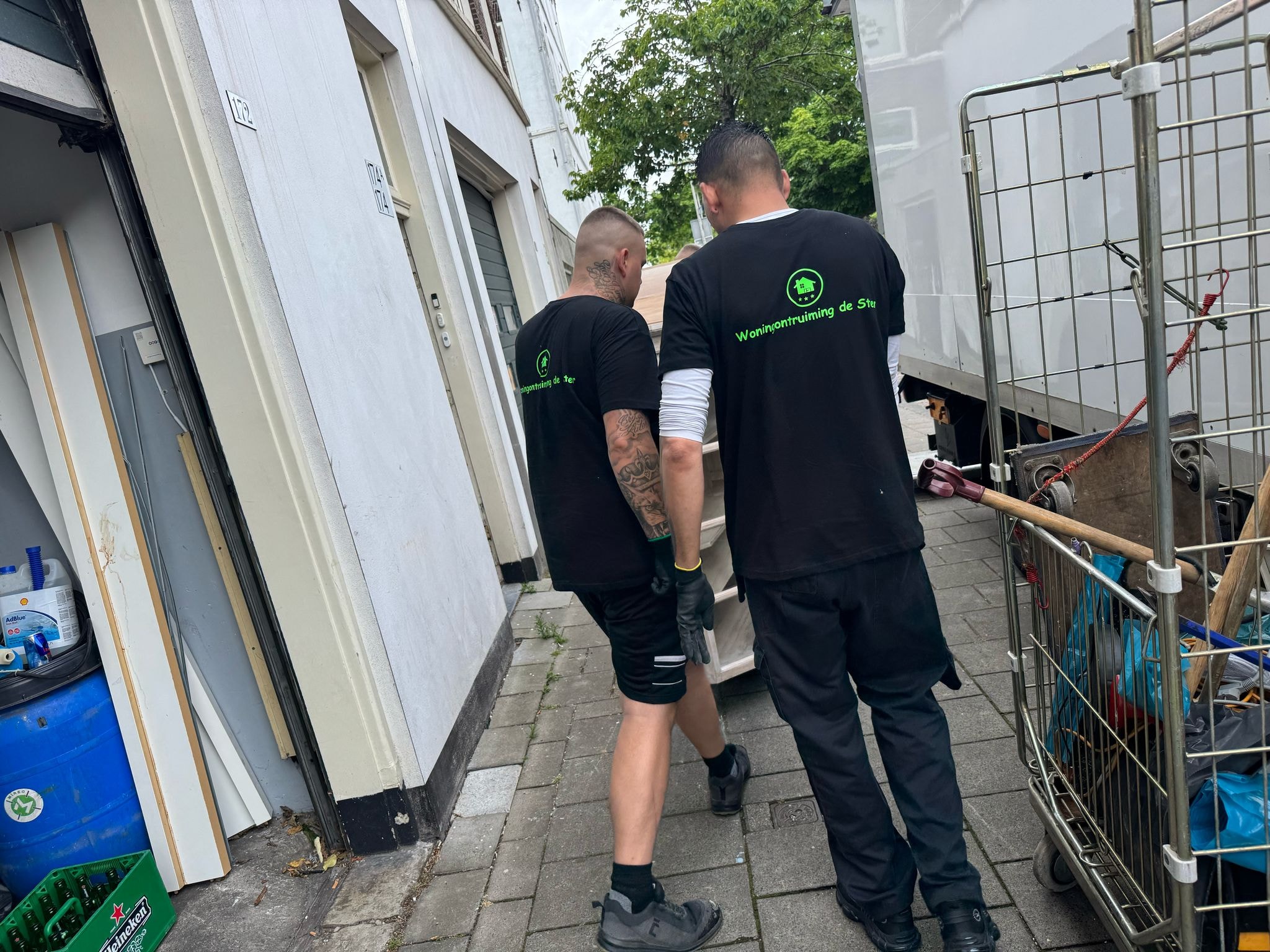 Medewerkers met rolcontainer bij een pand