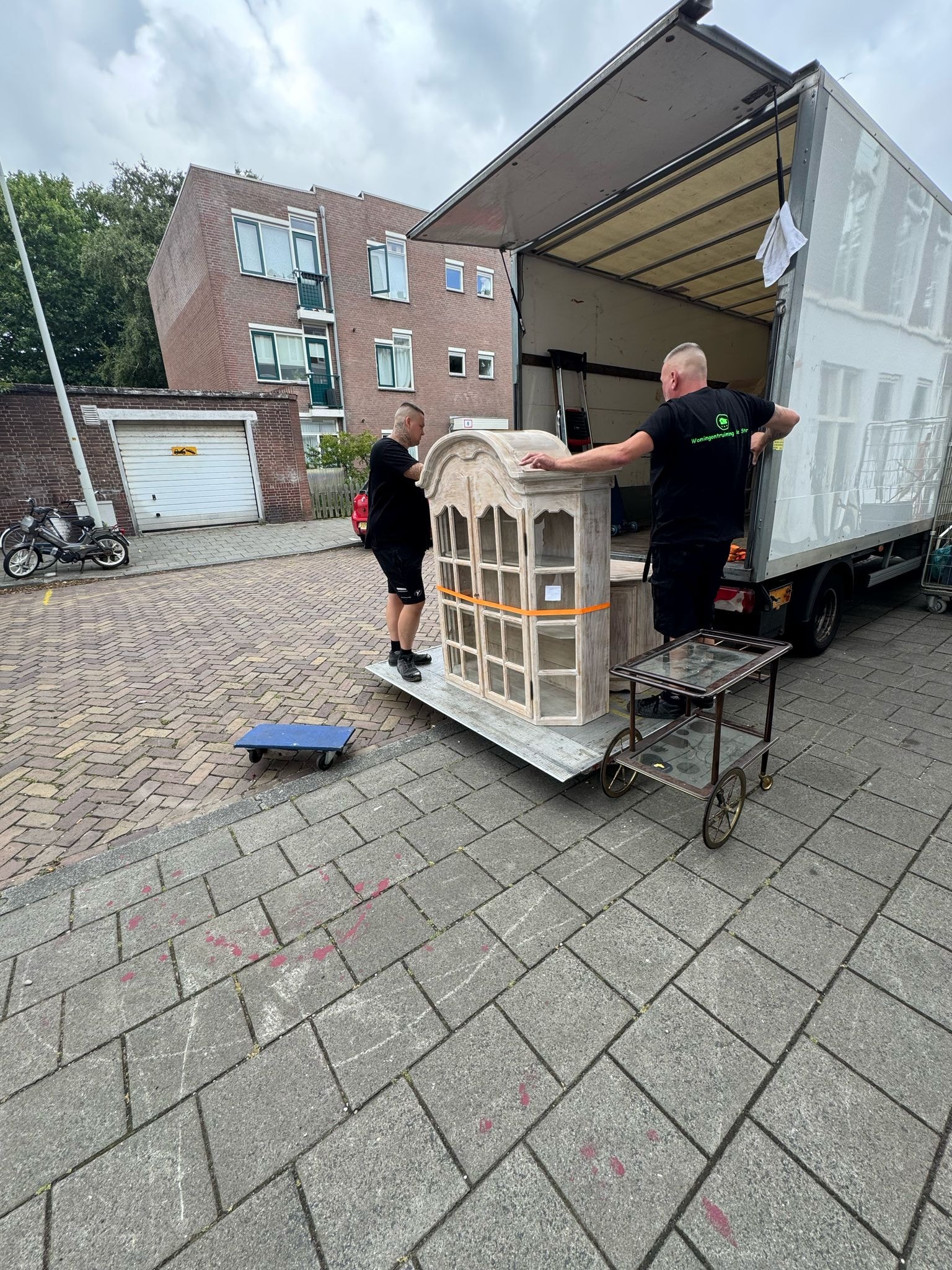 Medewerker verplaatst een kast op een steekwagen